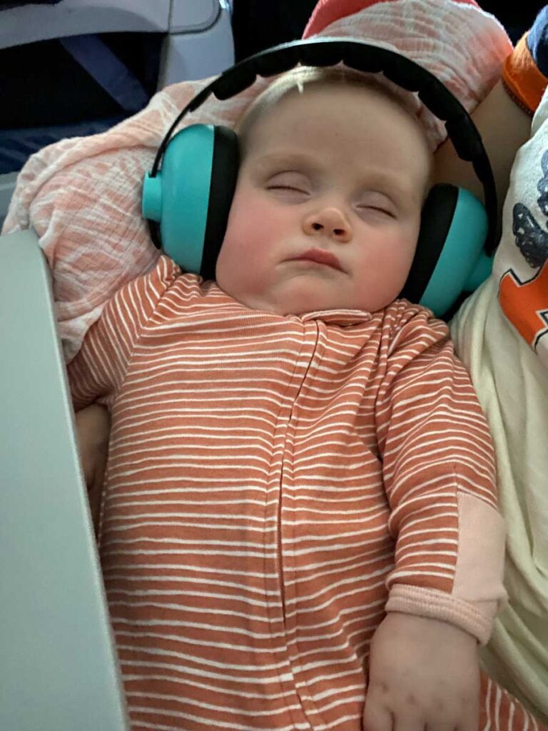 baby wearing noise canceling headphones on airplane