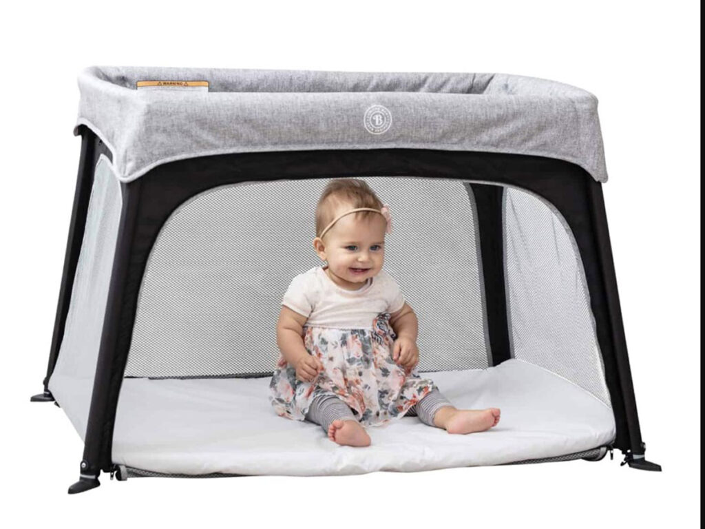 Lumiere Baby Travel Crib with baby sitting inside and front panel open