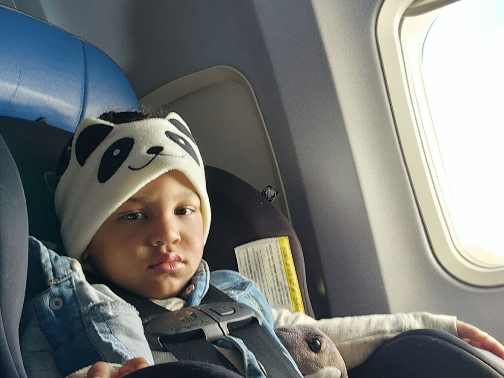 a child wears CozyPhones Headband Headphones for Toddlers on Airplane with a cute panda design.