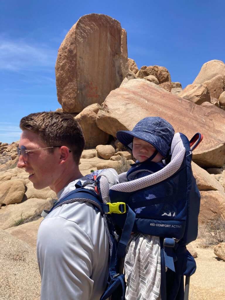 father with backpack carrier Hiking in Joshua Tree National Park with a Baby