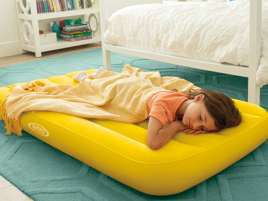 girl sleeping on yellow inflatable travel bed for toddlers by Intex.