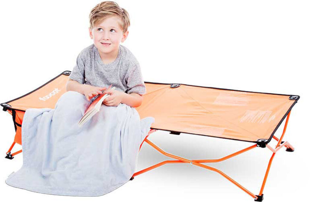 Boy with blanket sitting on Joovy Foocot toddler bed for travel.