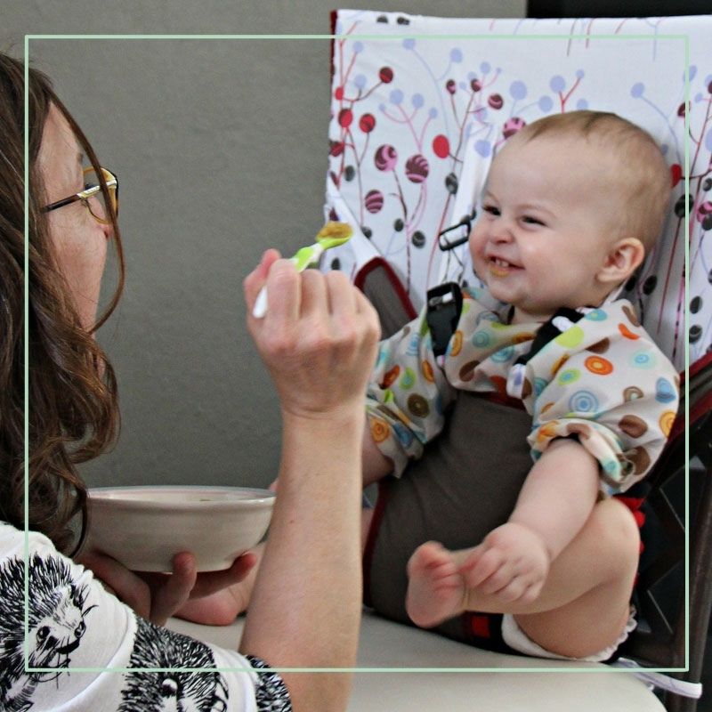 mother feeding baby in travel high chair