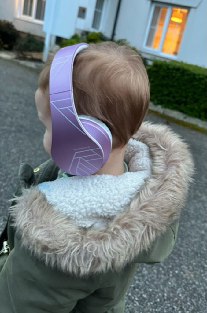 a child wears a pair of lavender colored PowerLocus Bluetooth Wireless Toddler Headphones.