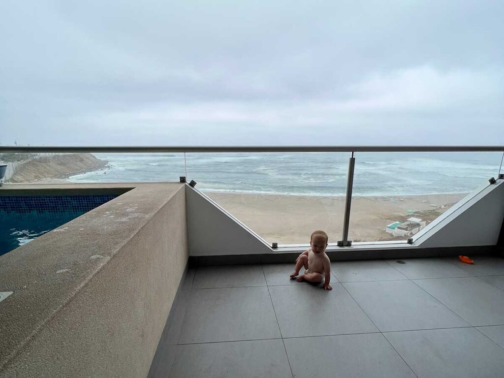 baby sitting on floor with beach in background - Punta Hermosa with a baby or toddler (Peru)