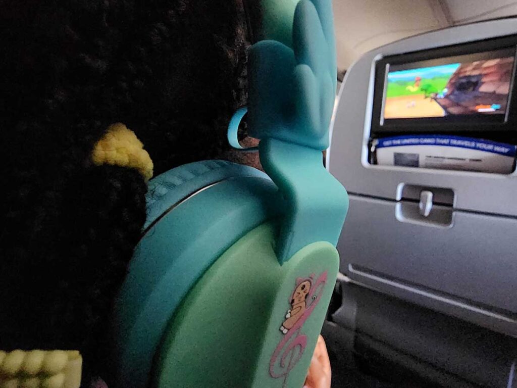 a young child watches a movie using Riwbox BT05 Wireless headphones for toddlers on planes.