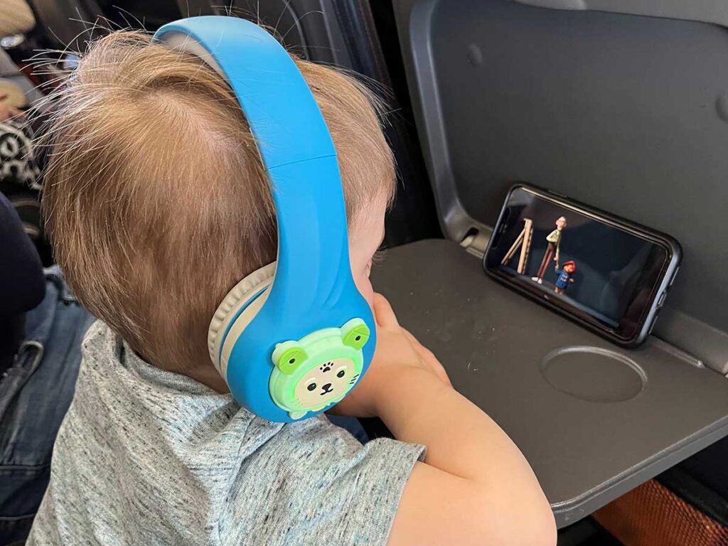 a small child watches a movie using Riwbox Baosilon FB-7S Frog Best Toddler Headphones for Planes.