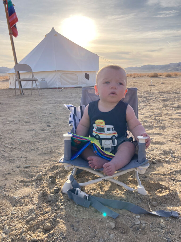 baby on portable high chair outside of glamping tent - Where to Stay in Joshua Tree with a Baby