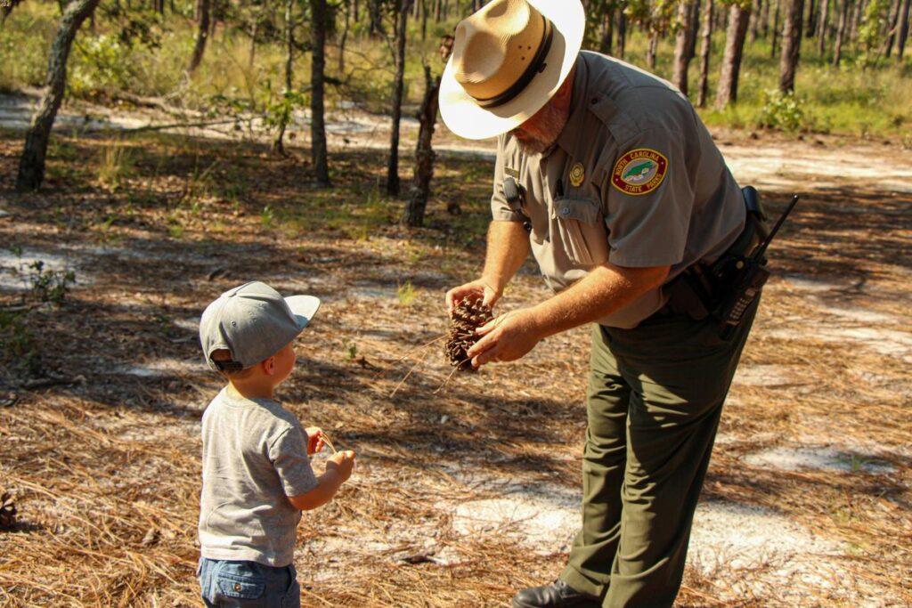 a toddler talks to a park ranger while on a family vacation to wilmington, north carolina