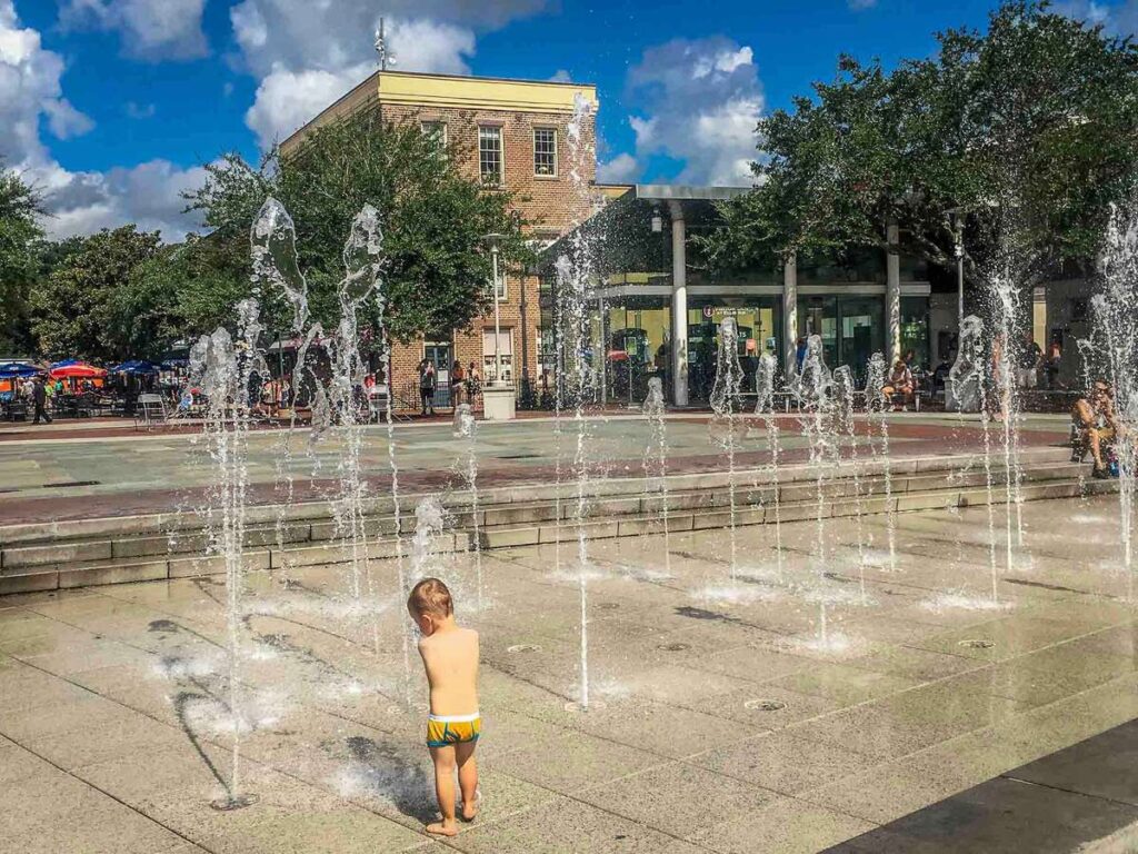 a toddler plays in a splash park in Ellis Square while on a family vacation to Savannah, GA