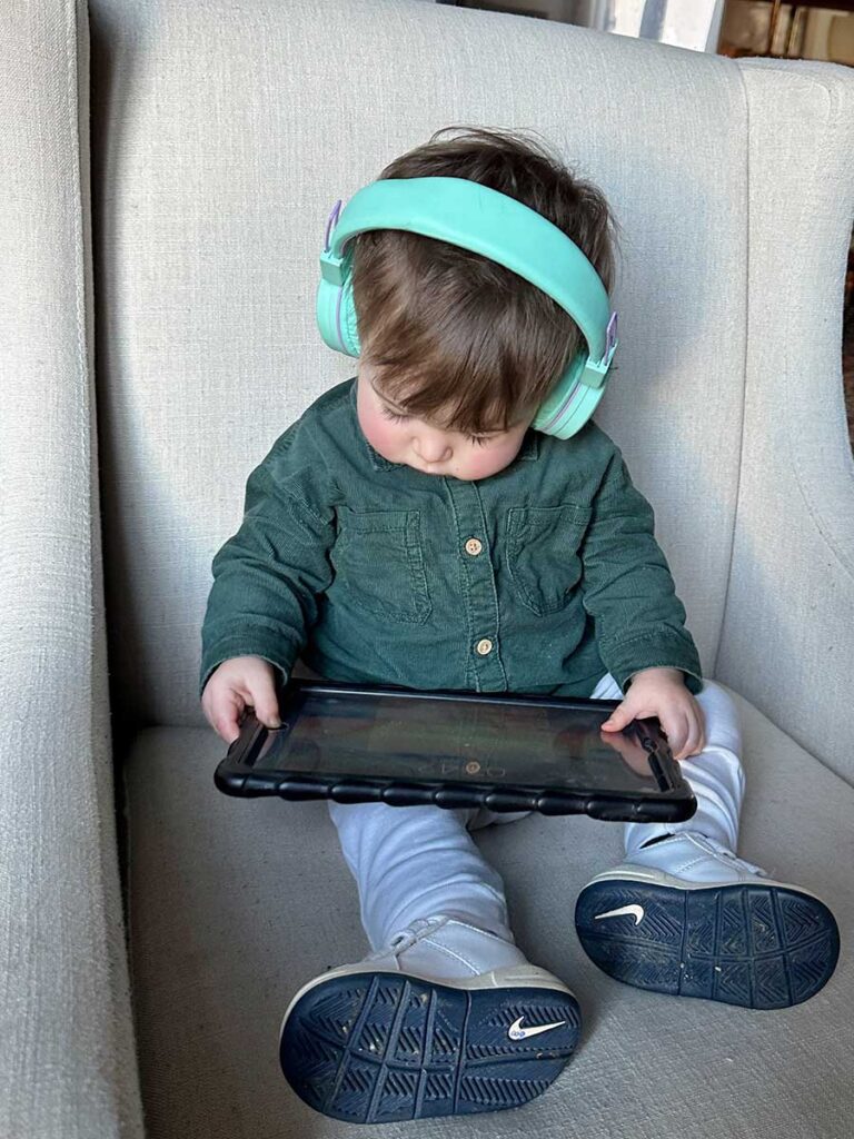 a toddler watches a show on a tablet using iClever Kids Bluetooth Headphones for toddlers.