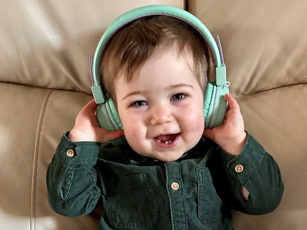 a small child listens to iClever Kids Bluetooth Headphones for toddlers.