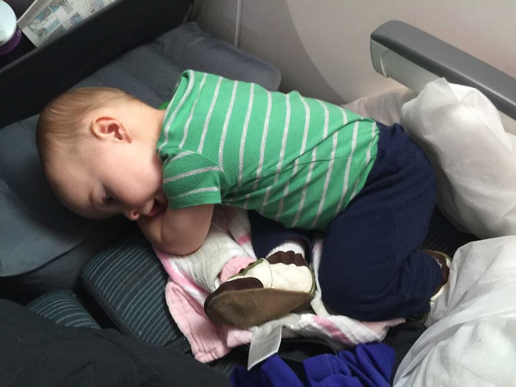 a toddler lies down on an inflatable airplane cushion.