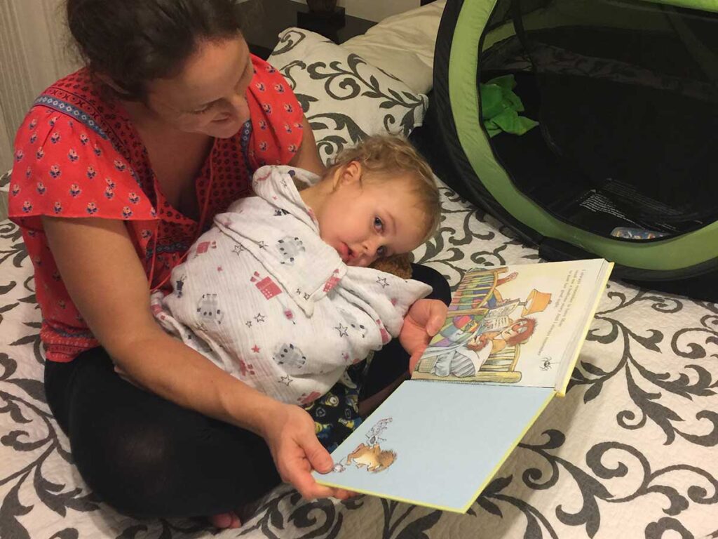 Celine Brewer, owner of BabyCanTravel.com, reads a bedtime story to her toddler while on a family vacation.