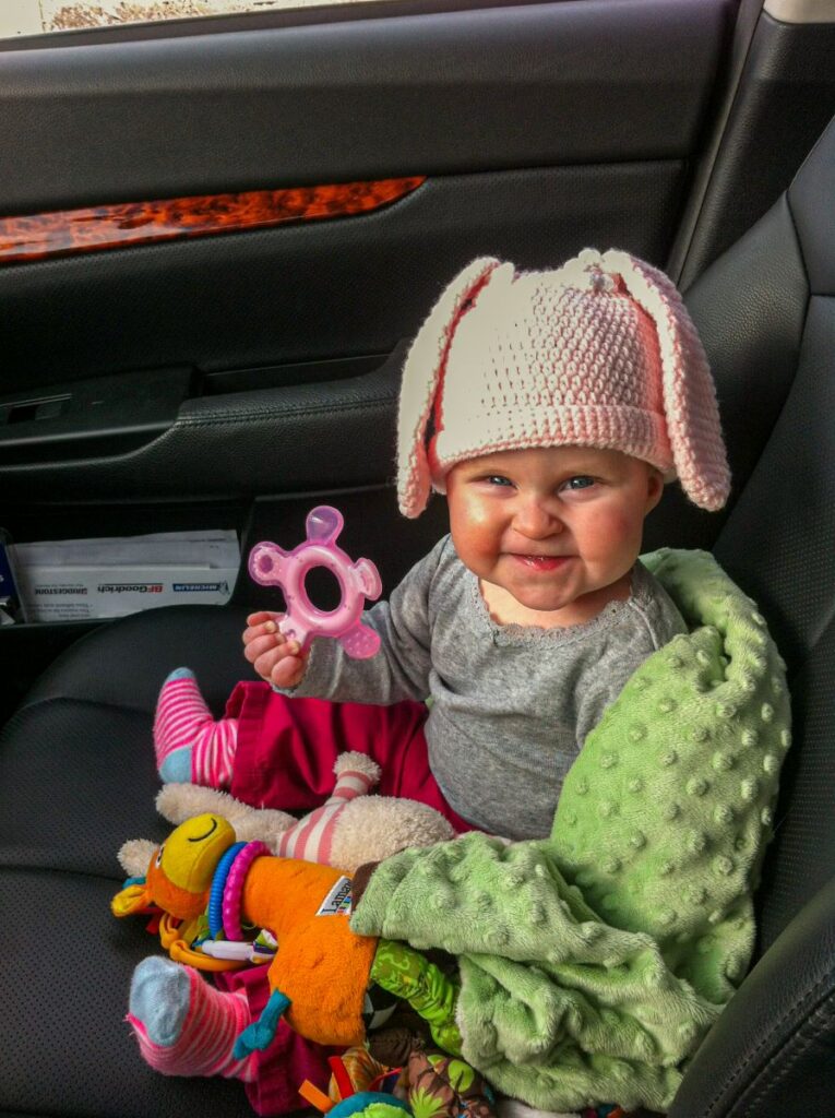 a cute baby shows off her toys before going on a long road trip.