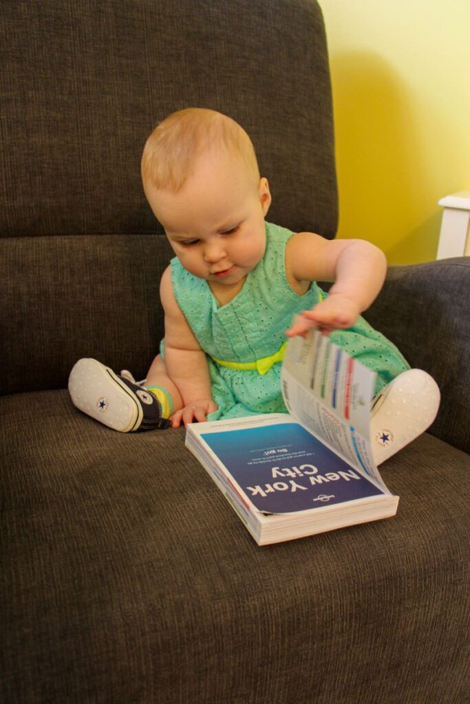 A baby flips through a Lonely Planet Guide on New York City.