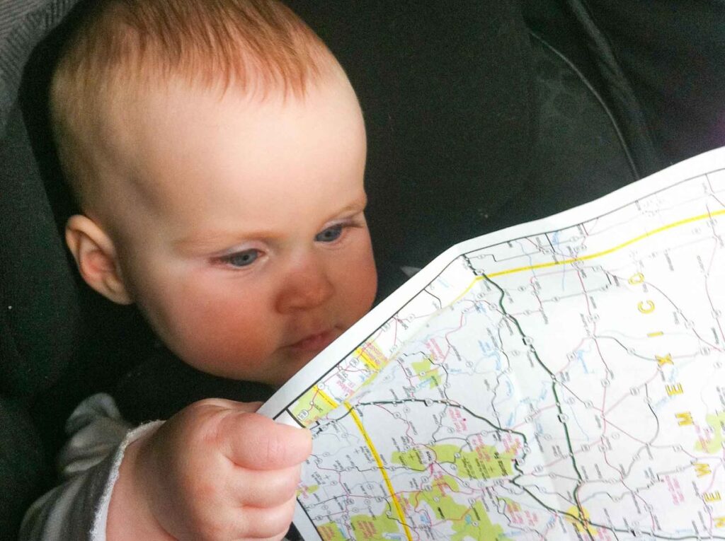 a cute baby looks at a road map.