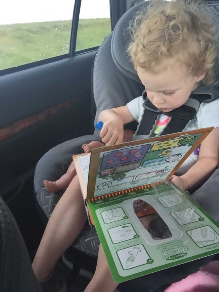 a 2 year old toddler using Melissa & Doug Water Wow activity book in the car.