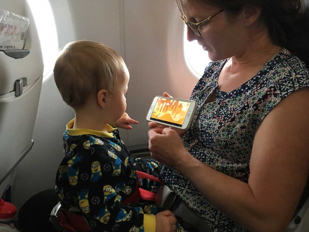 Celine Brewer, of the Baby Can Travel website, uses apps on her iPhone as airplane activities for an 18 month old.