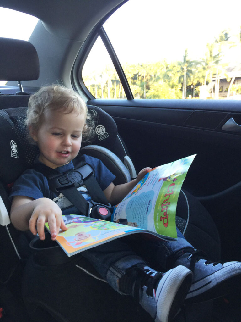 a BabyCanTrvel.com toddler reads a Chirp magazine, keeping him entertained during a family road trip.