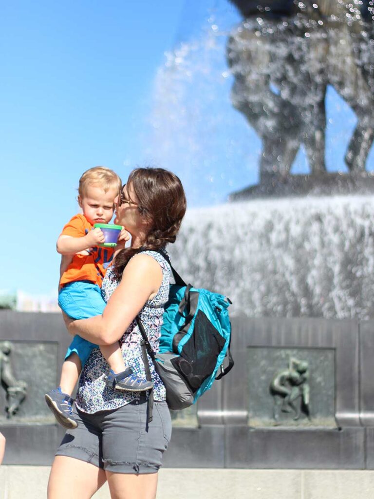 Celine Brewer, owner of BabyCanTravel.com, wears a diaper bag backpack in Oslo, Norway, which frees up her hands to hold her toddler.