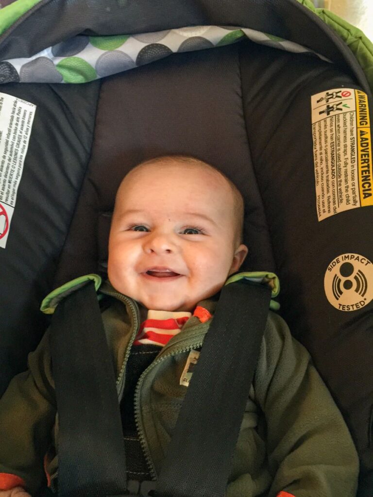 a smiling baby is strapped into his car seat while on a family road trip to Sedona, AZ.