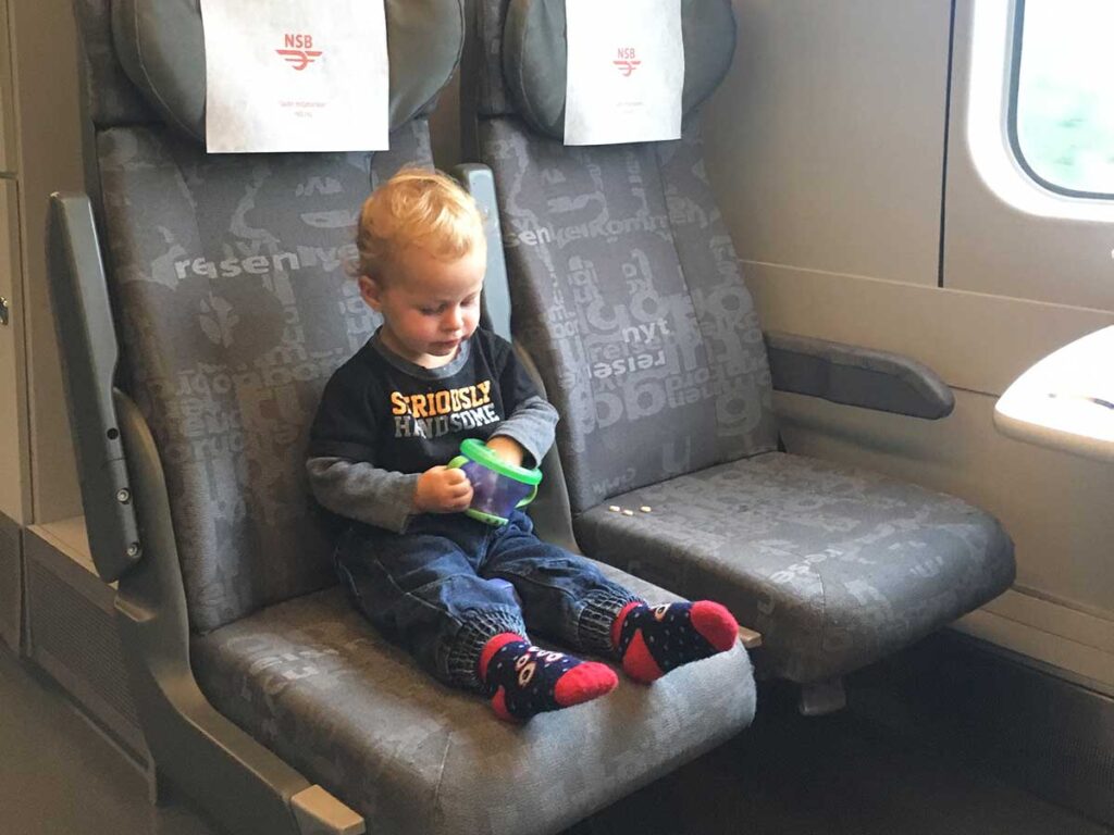 toddler eating cheerios out of snack cup on train.