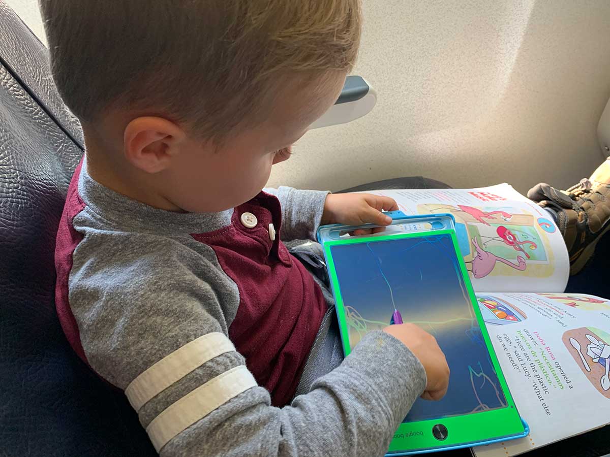 toddler playing with LCD tablet travel toy on airplane.