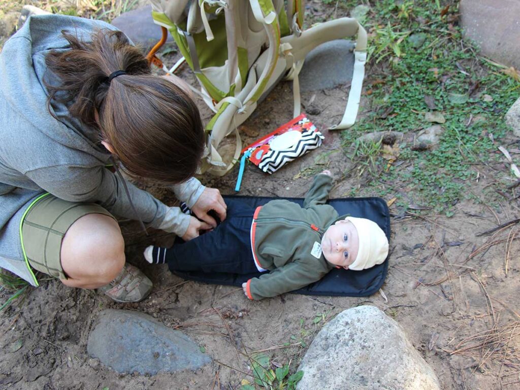 Changing baby's diaper on a portable change mat while hiking.