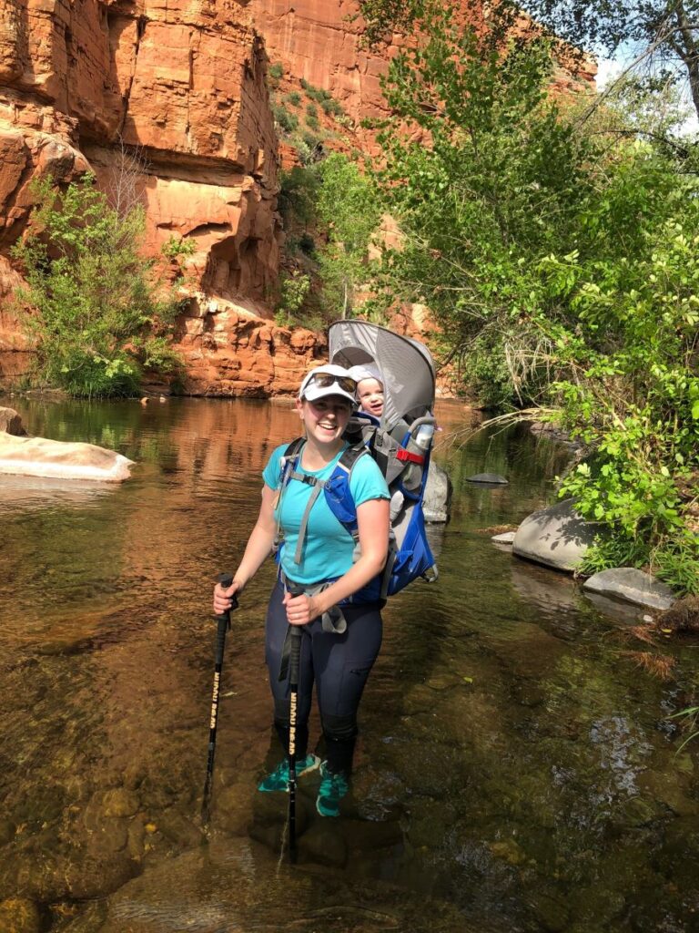 a mom carries her baby in an Osprey Poco backpack carrier while on a family hike.