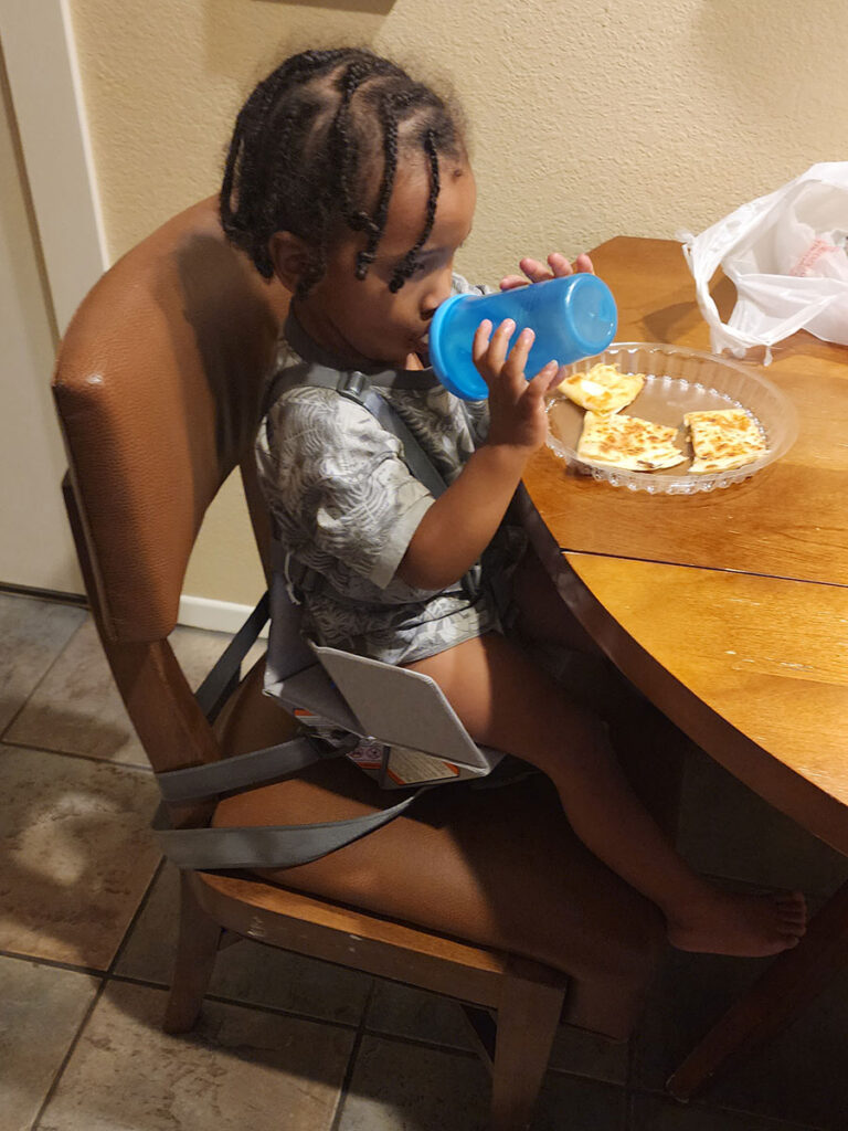 child sitting in Bombol Booster eating and drinking.