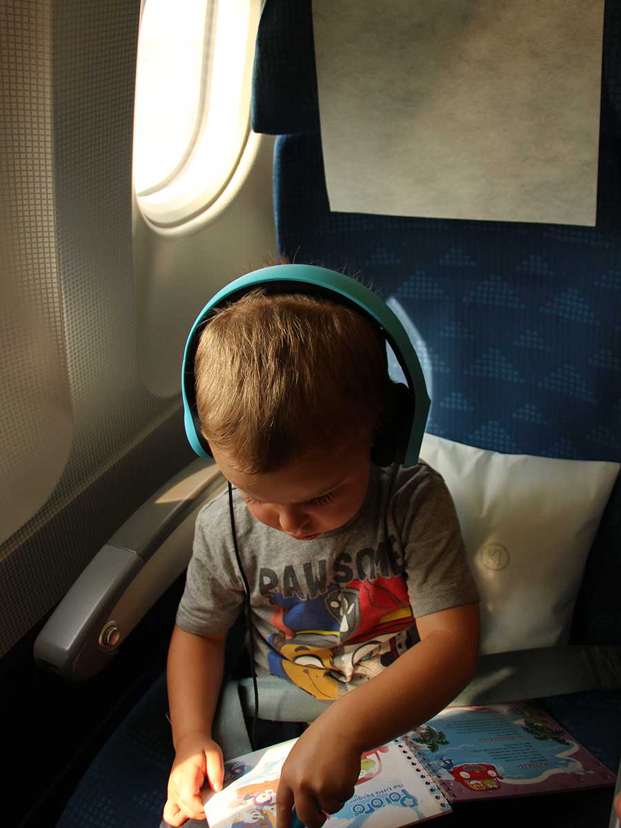 a toddler from BabyCanTravel.com wears Lil Gadgets toddler headphones on an airplane.