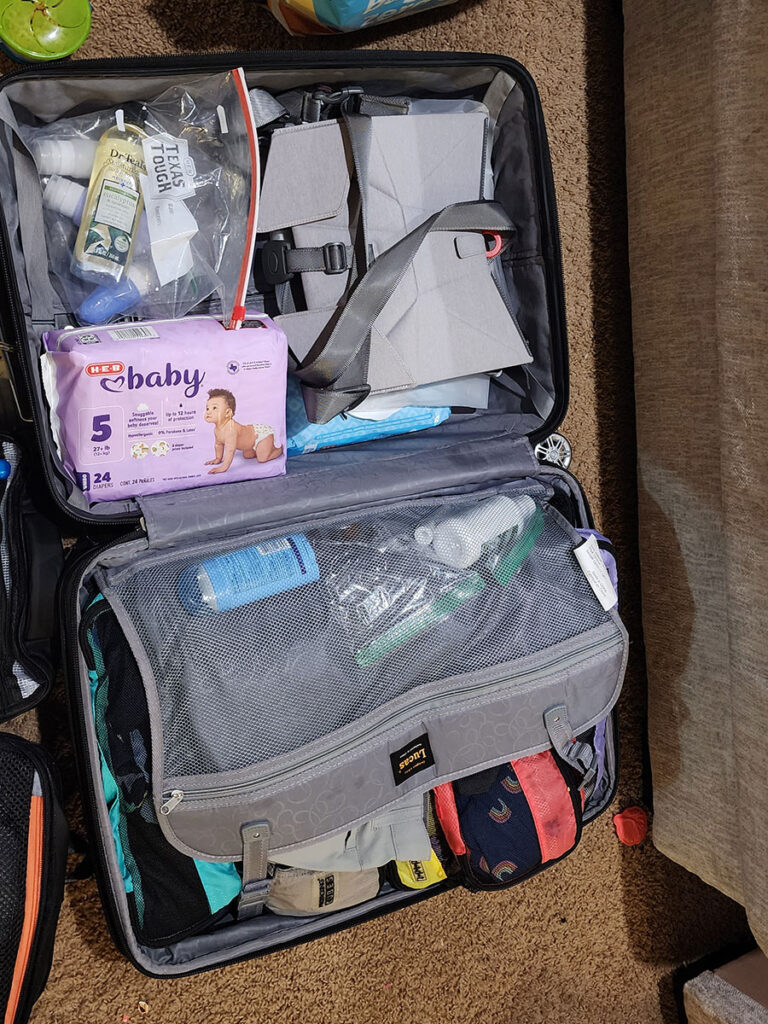 Bombol Booster seat and other items packed in suitcase for toddler.