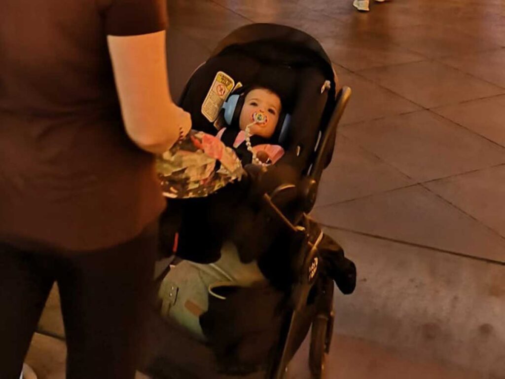 a baby wearing baby banz headphones in stroller.