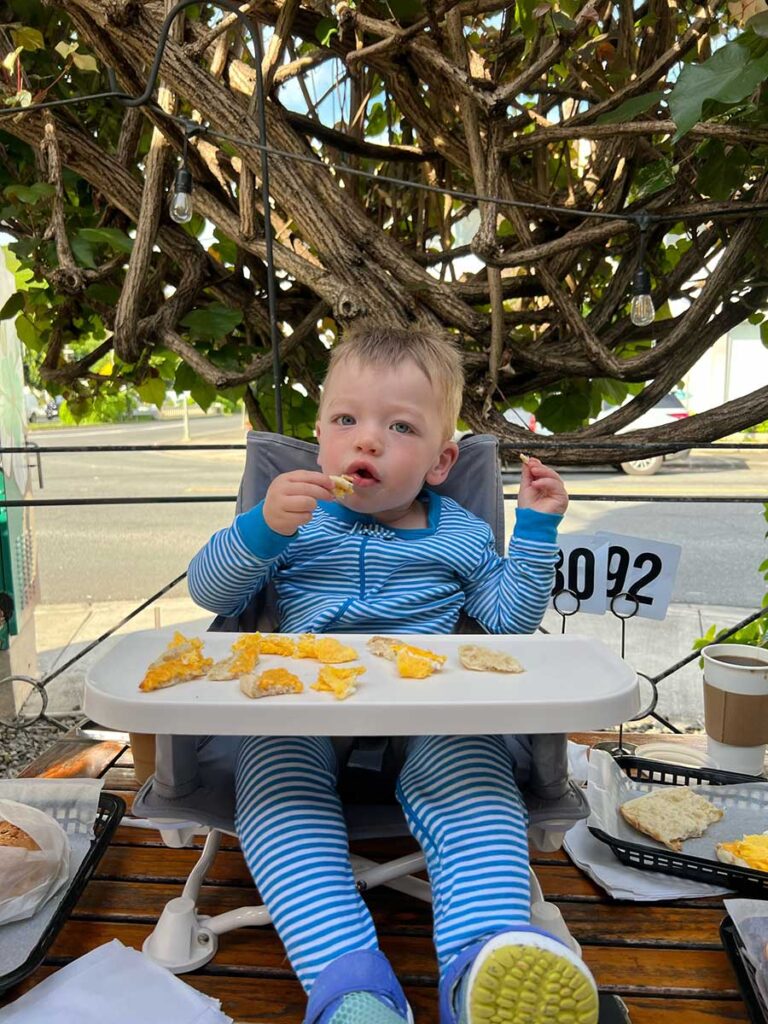 a baby sits in a hiccapop OmniBoost Booster seat during snack time.