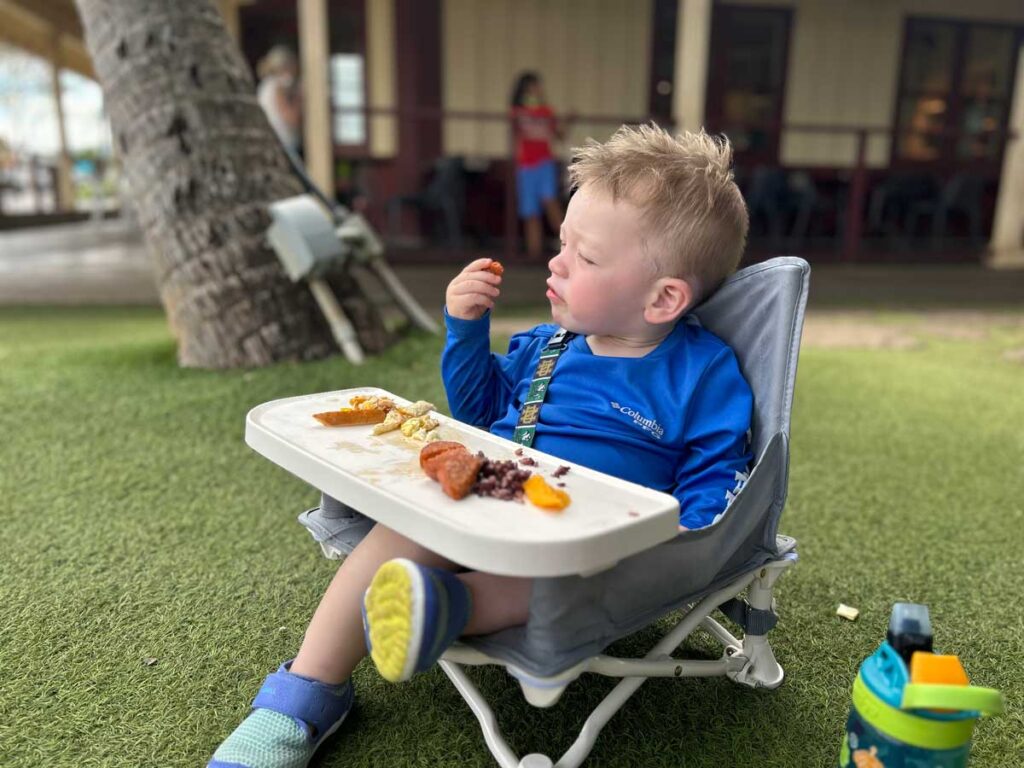 a toddler eats a snack in his hiccapop Booster Seat.