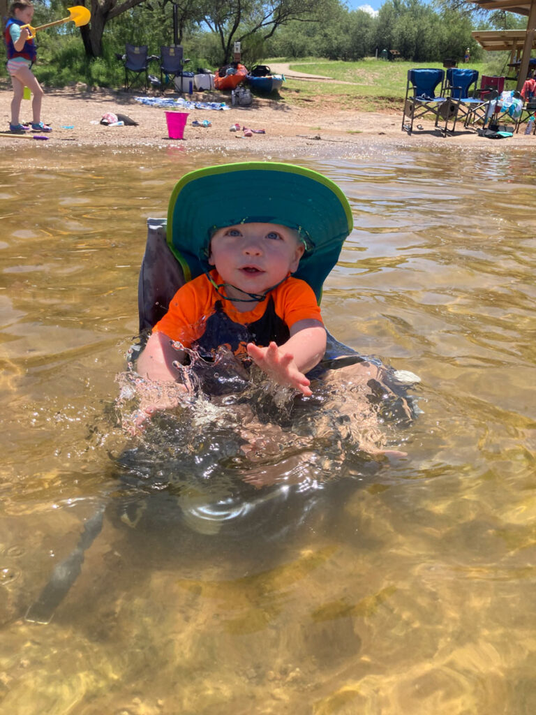 Baby in a booster seat in the water. 