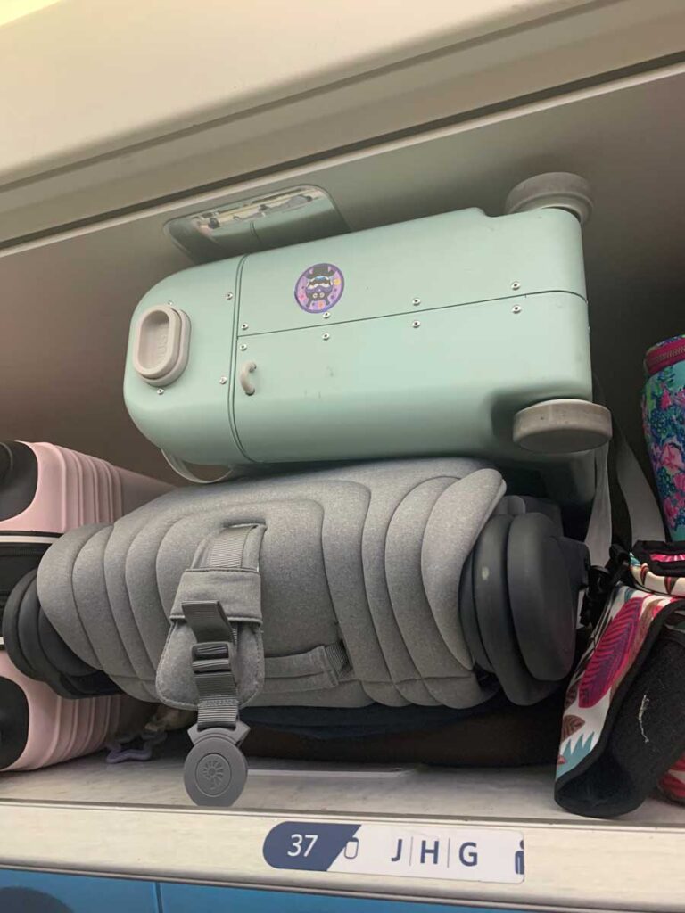 An ErgoBaby stroller being stored in overhead bin on an airplane. 