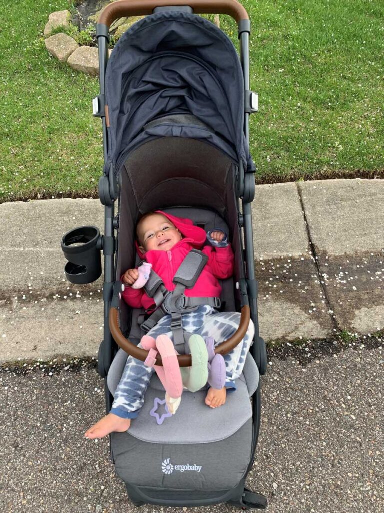 A smiling baby lying down in a stroller. 