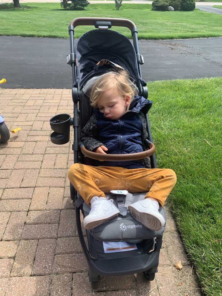 Toddler sleeping in an ErgoBaby stroller. 