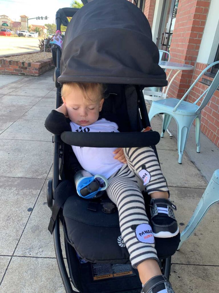 toddler sleeping in a travel stroller.