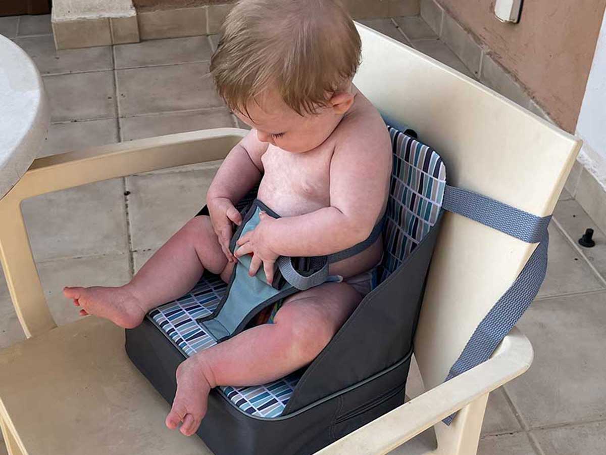 Baby sitting in Nuby Travel Highchair.