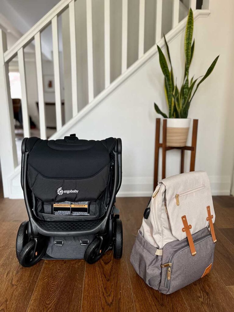 ErgoBaby Metro+ Stroller folded next to diaper backpack bag.