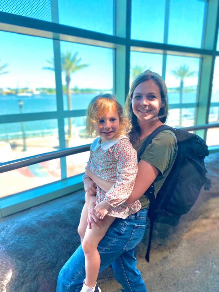 Mom holding daughter in front of window. 