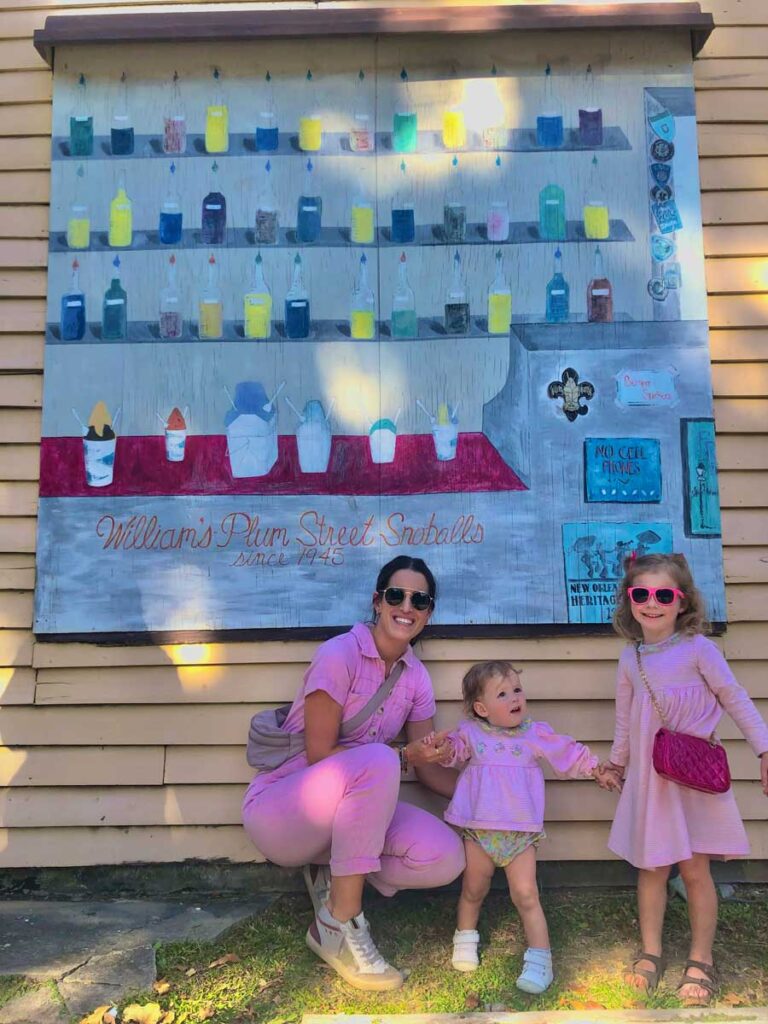 woman and girls standing in front of a mural.