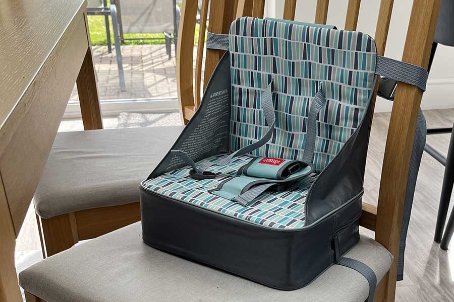 Nuby Easy Go Booster Seat for Travel strapped to chair.