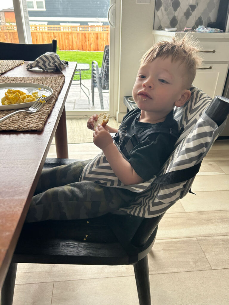 toddler sitting in Original Easy Seat travel highchair.