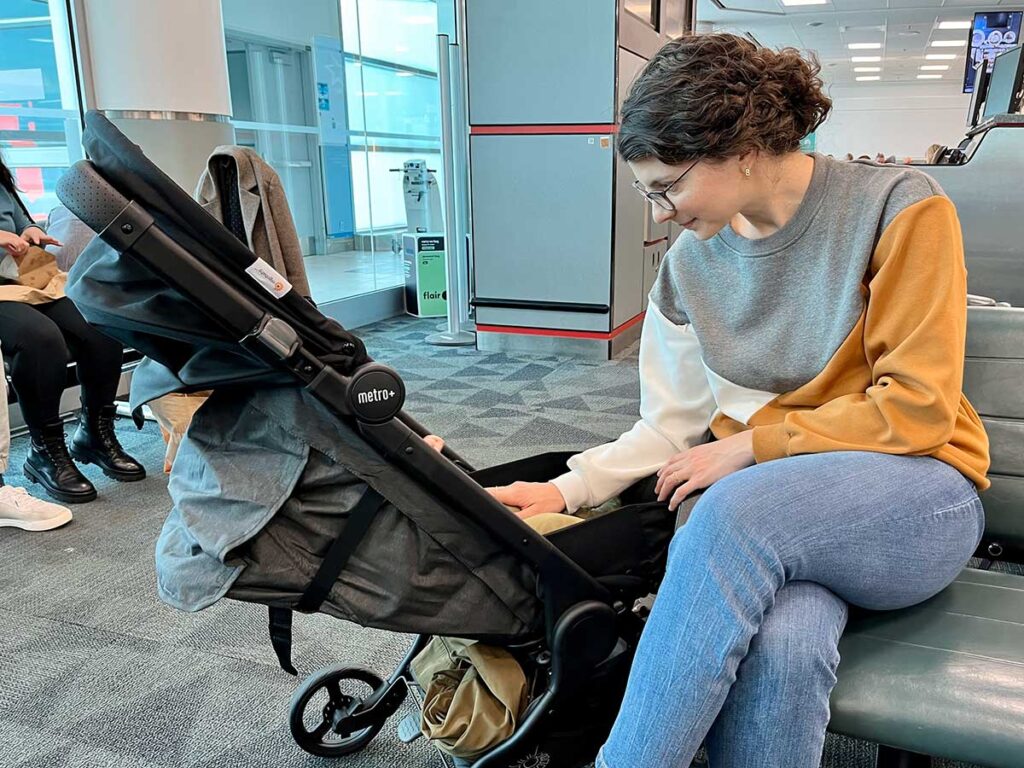 Woman using ErgoBaby Metro+ Stroller for travel at airport.