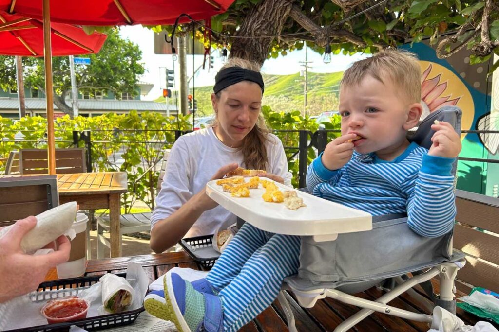 Baby eating while sitting in a booster chair that is on a table.