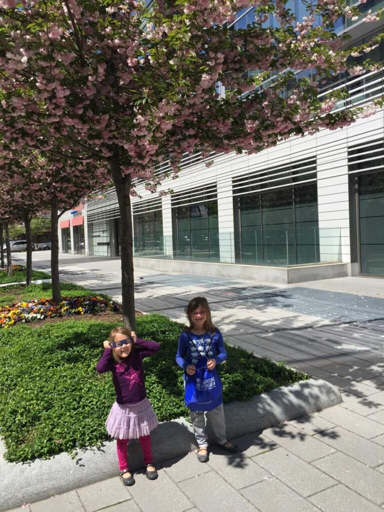 2 girls standing by sidewalk.